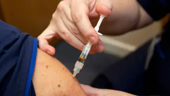 A person receives a vaccination from a healthcare professional