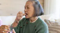 An older woman takes medication with a glass of water