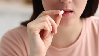 A woman ingests a white tablet