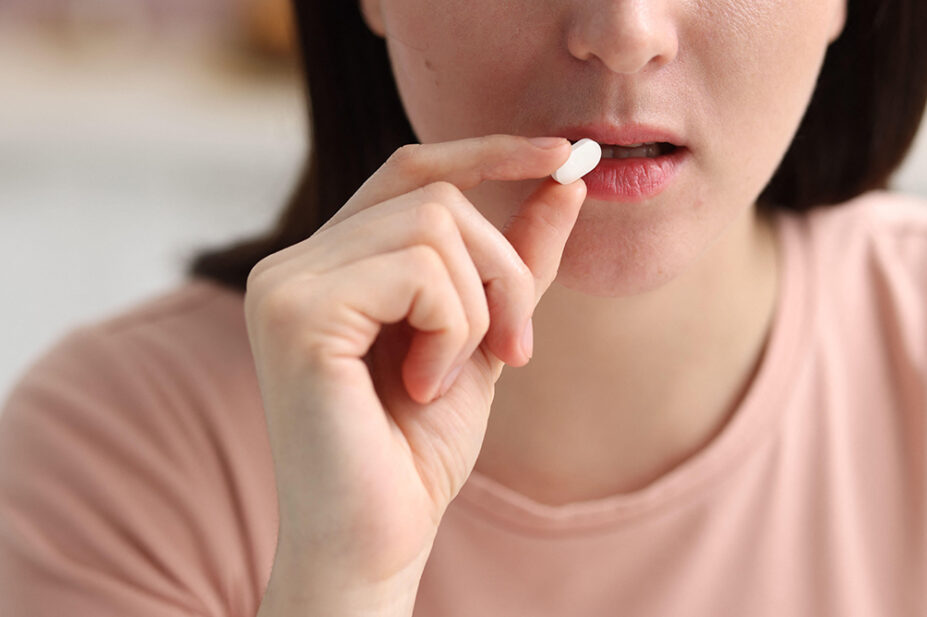 A woman ingests a white tablet
