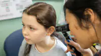 A healthcare professional examines a patient's ear