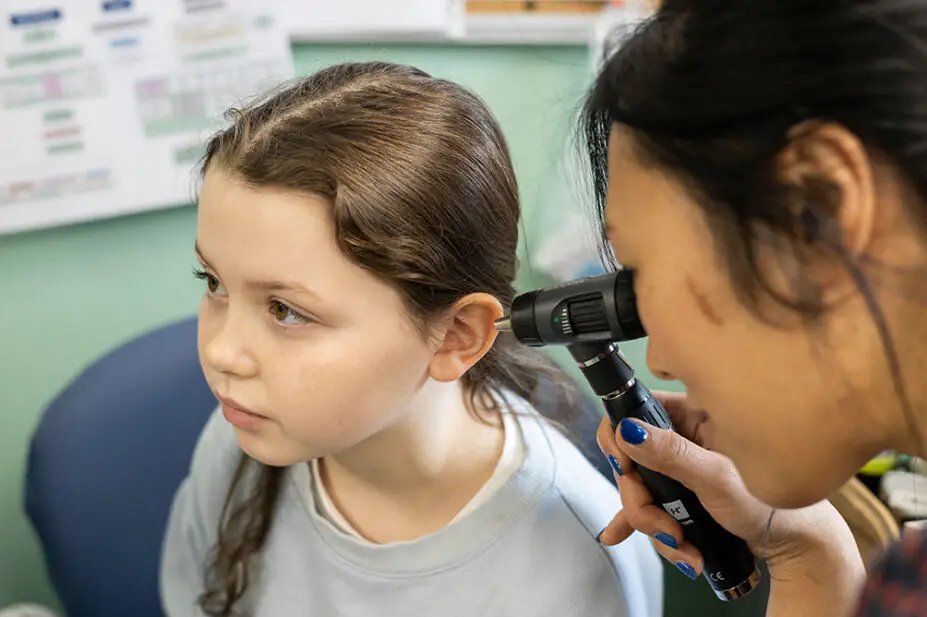 A healthcare professional examines a patient's ear