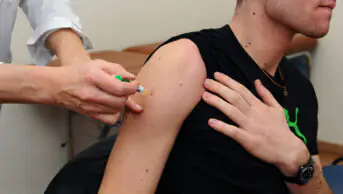 A young man receives a vaccine from a healthcare professional