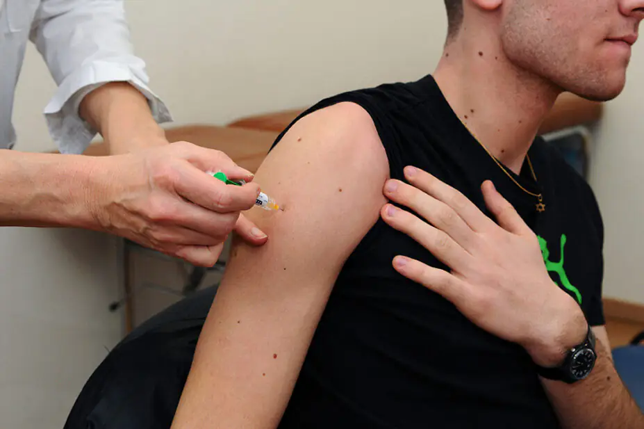 A young man receives a vaccine from a healthcare professional
