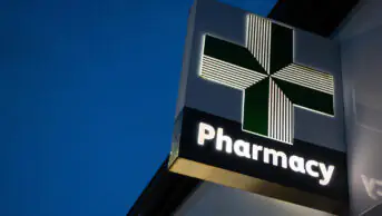An image of a community pharmacy's illuminated sign at night
