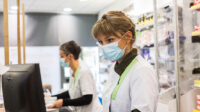 Community pharmacists work while wearing face masks