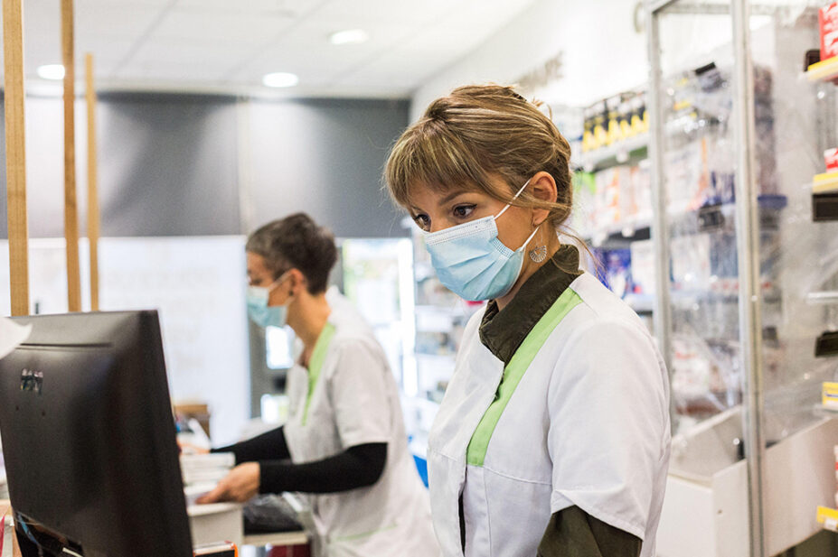Community pharmacists work while wearing face masks