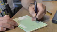 A pharmacist writes a prescription on a pad