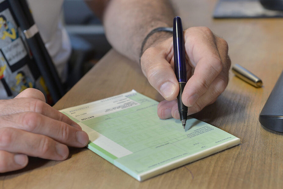 A pharmacist writes a prescription on a pad