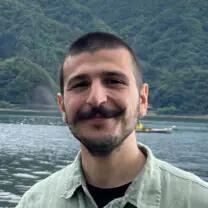 Vasileios smiles in front of a lake
