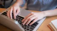 Close-up of hands typing on laptop