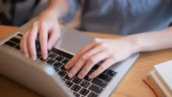 Close-up of hands typing on laptop