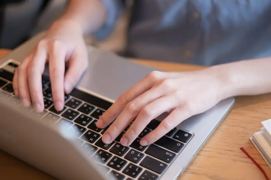 Close-up of hands typing on laptop