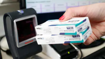 A pharmacist scans barcodes on boxes of medicine