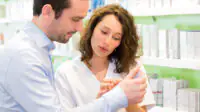 A pharmacist assists a patient in a community pharmacy