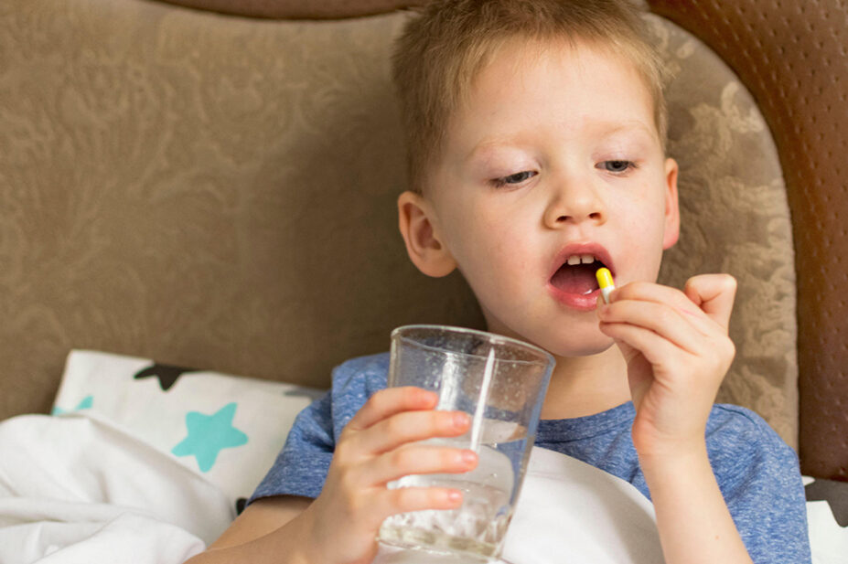 A child takes a tablet with a glass of water
