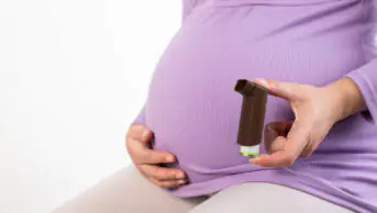 A pregnant woman holds a brown inhaler