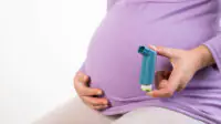 A pregnant woman holds an inhaler
