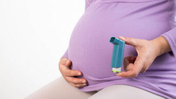 A pregnant woman holds an inhaler