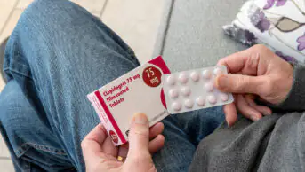 Close up of man person holding blister pack of Clopidogrel tablets pills tablet