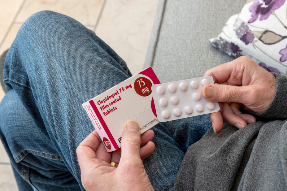 Close up of man person holding blister pack of Clopidogrel tablets pills tablet