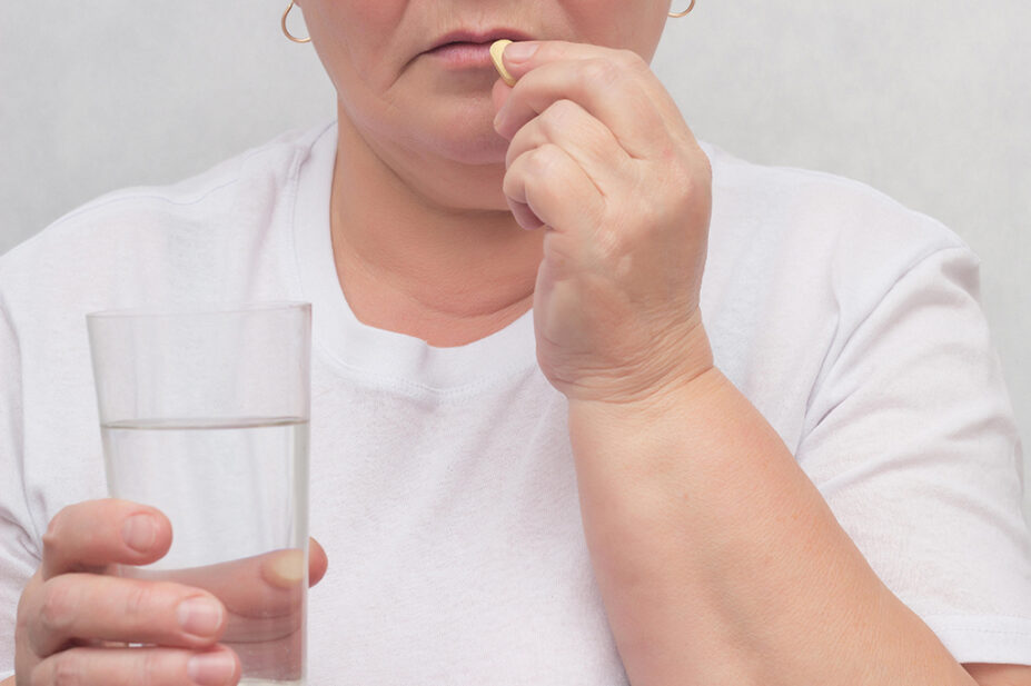 A woman takes a pill with a glass of water