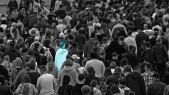 Lots of people in a crowd, black and white image with one person in light blue