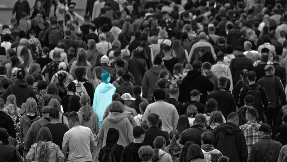 Lots of people in a crowd, black and white image with one person in light blue