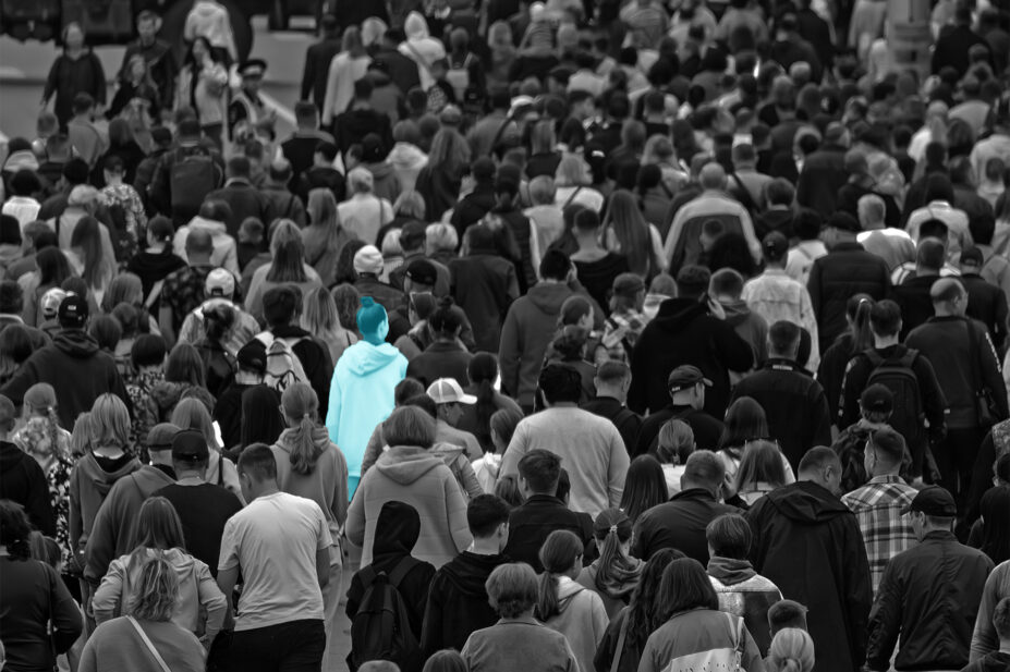 Lots of people in a crowd, black and white image with one person in light blue