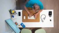 Birds-eye view of a male GP working at a desk, typing on a keyboard.