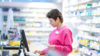 A pharmacist works on the computer in a community pharmacy