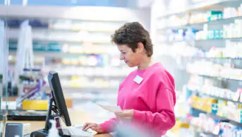 A pharmacist works on the computer in a community pharmacy