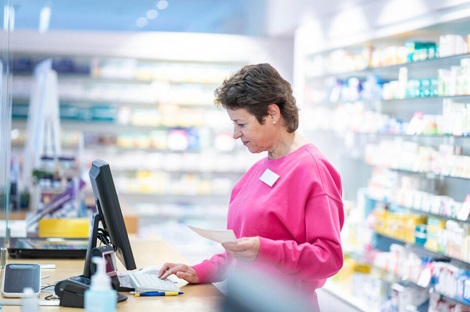 A pharmacist works on the computer in a community pharmacy
