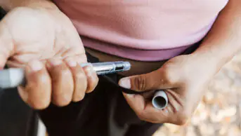 A woman injects herself with a weight-loss pen