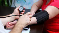A woman has her blood pressure checked by a healthcare professional