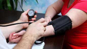A woman has her blood pressure checked by a healthcare professional