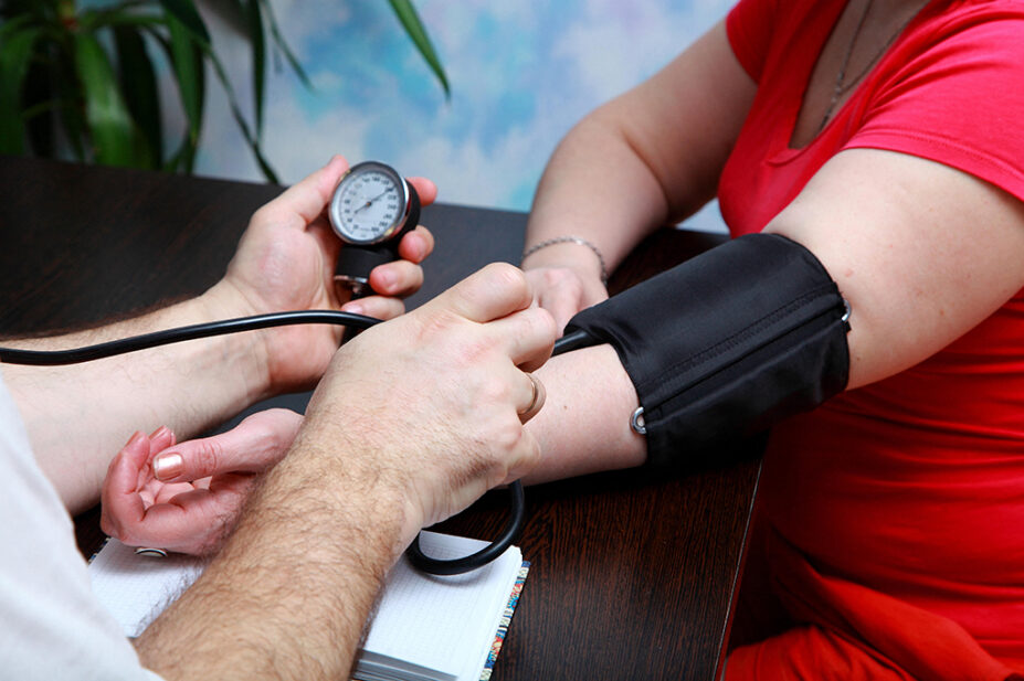A woman has her blood pressure checked by a healthcare professional