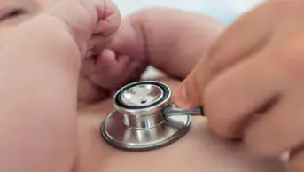 Doctor listens the heart to small newborn with stethoscope