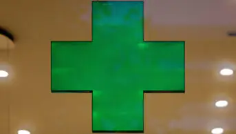 A green cross sign in a community pharmacy