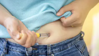A person injects a weight loss pen into their abdomen