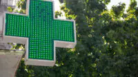 A green cross sign outside of a community pharmacy