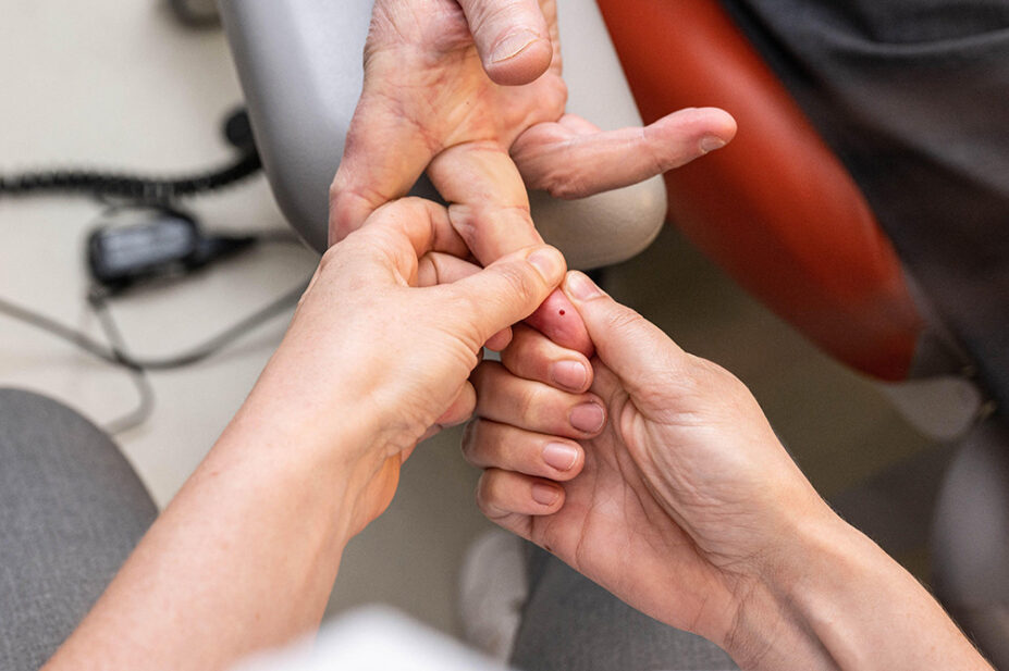 A patient undergoes a finger prick test for cholesterol