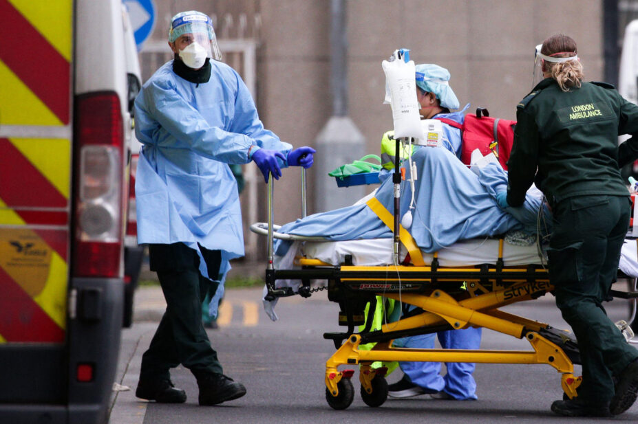 Medics wearing PPE transport a patient into the emergency department of the Royal London Hospital in London, England