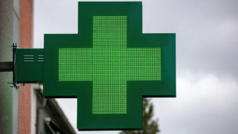 The green cross sign outside of a community pharmacy
