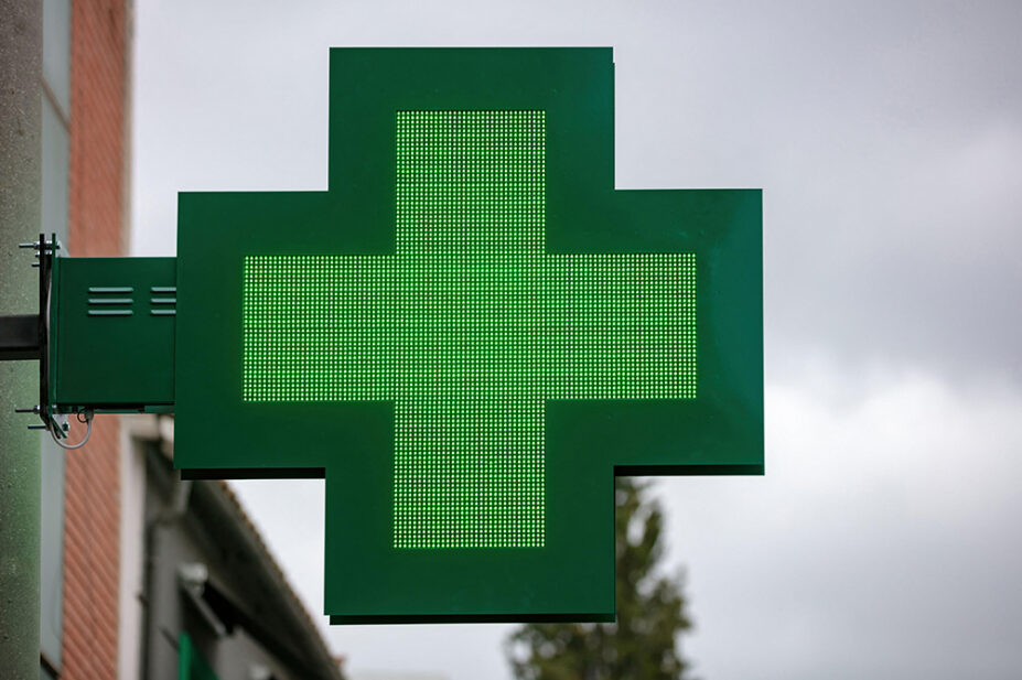 The green cross sign outside of a community pharmacy