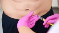 A man receives an injection in his abdomen