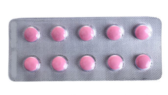 Pink coloured pills packed in blister isolated on white