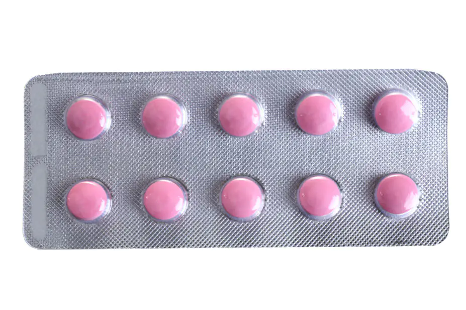 Pink coloured pills packed in blister isolated on white