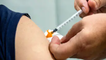 A healthcare professional gives a person a vaccination in their arm