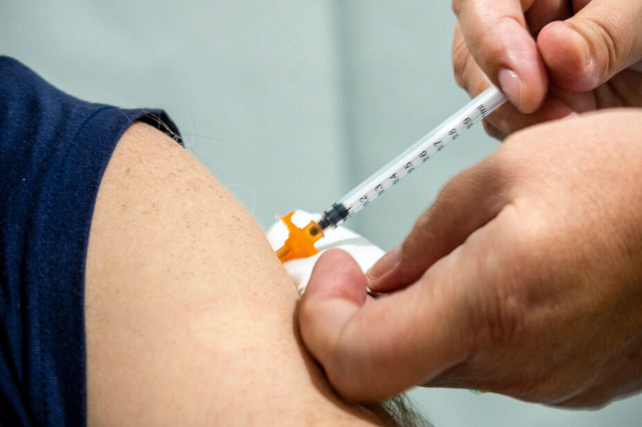 A healthcare professional gives a person a vaccination in their arm